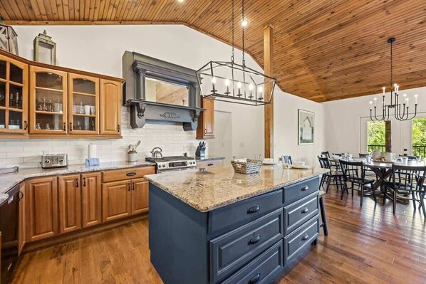 A kitchen with wooden cabinets, a granite countertop, and a dining area with a table and chairs.