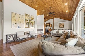 Un salon spacieux doté d’un haut plafond, de poutres en bois et d’une grande fenêtre laissant entrer la lumière naturelle.