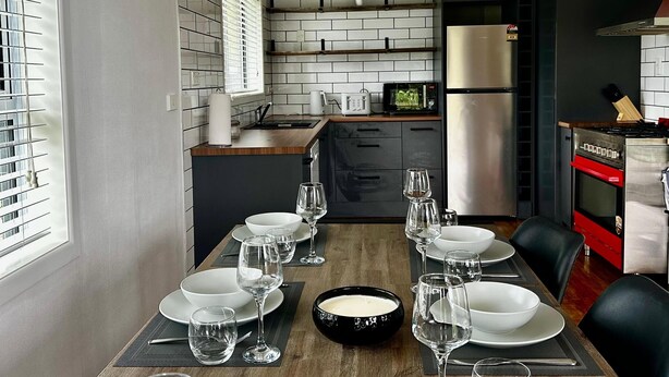 A modern kitchen with a dining area set for a meal. - Ruby’s Nest – A countryside experience (Te Poi)