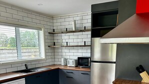A modern kitchen with a dishwasher, microwave, refrigerator, and gas stove. - Ruby’s Nest – A countryside experience (Te Poi)