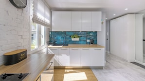 A modern kitchen with white cabinets, a blue backsplash, and a wooden countertop.