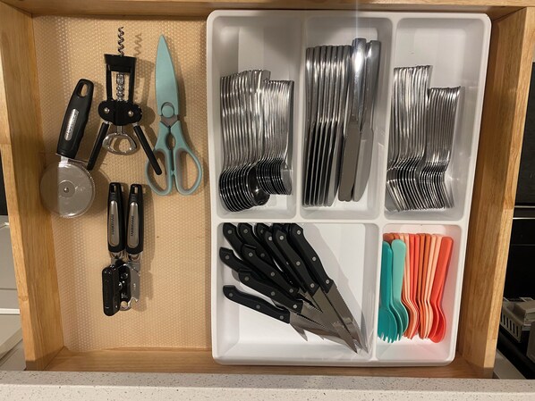 A kitchen drawer with various utensils and tools organized in compartments.