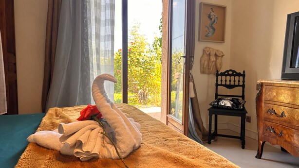 Una habitación con una cama, un tocador de madera, una silla y una ventana con vistas a la vegetación.