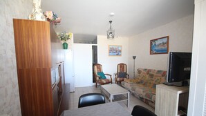 Una sala de estar con un aparador de madera, un sofá, un televisor y una mesa de comedor.