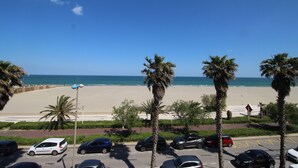 Un estacionamiento con varios coches, una playa y palmeras al fondo.