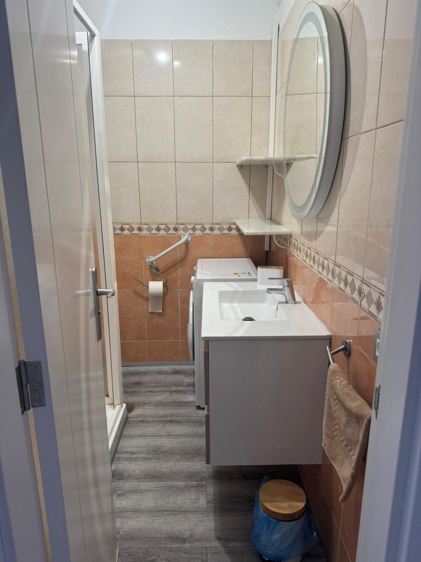 A narrow bathroom with a white sink, a mirror, and a towel rack.