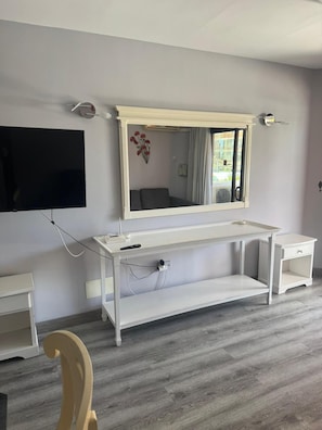 A room with a white vanity, a flat-screen TV mounted on the wall, and a wooden chair. - Las Americas 1-bed Apt, Sleeps 5, Pool, Parking (Arona)