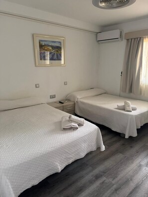 A hotel room with two single beds, a nightstand, a remote control, and a painting on the wall. - Las Americas 1-bed Apt, Sleeps 5, Pool, Parking (Arona)