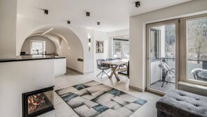 A modern interior with a kitchen, dining area, and a balcony with a view. - Villa Tribulaunblick – Luxury Apartment with Fireplace, Terrace & Mountain View (Gossensass-Colle Isarco)