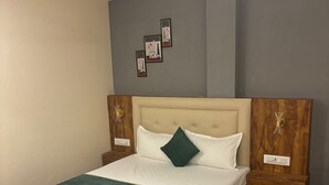 Un dormitorio con estructura de cama de madera, ropa de cama blanca, una manta verde y un ventilador de techo.