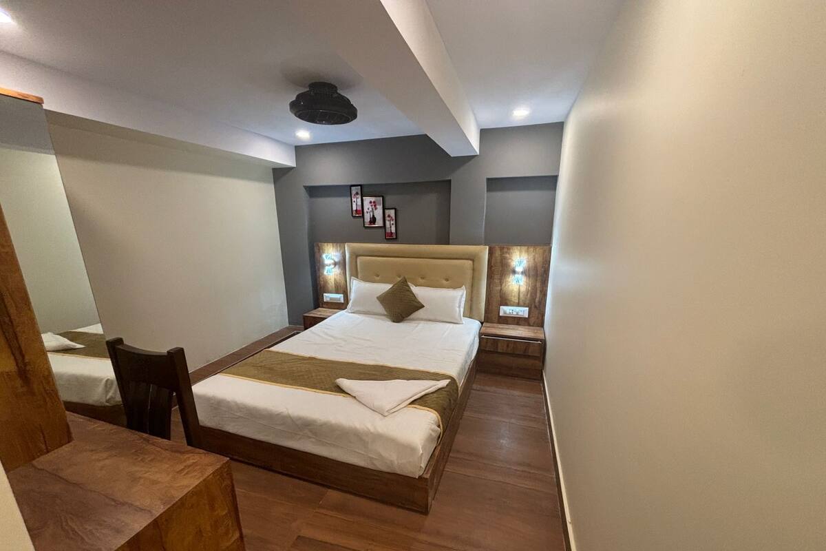 A hotel room with a large bed, two bedside tables, a wooden desk, and a chair.