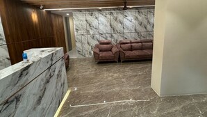 Un interior moderno con un mostrador de recepción, paredes de mármol, un sofá de cuero marrón y vigas de madera en el techo.
