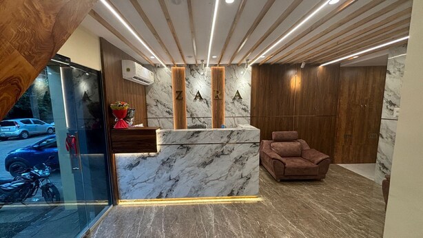 Una recepción con mostrador de mármol, paneles de madera y un sillón elegante.