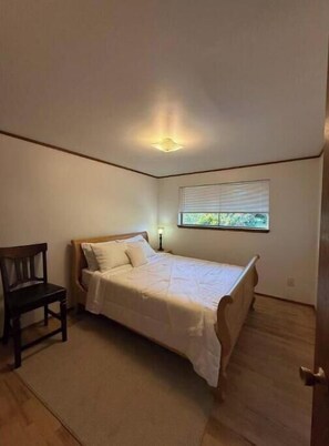 Cozy retreat with a single bed, nightstand, and chair, perfect for a peaceful stay.