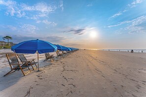 A beach with rows of blue umbrellas and beach chairs.