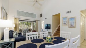 A dining area with a wooden table, white chairs, and dark blue placemats.