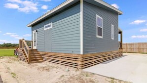 A single-story house with a wooden deck, a front door, and a small porch. - The Blue Flower (Rockport)