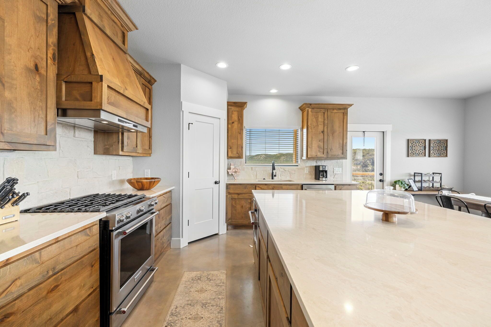 A modern kitchen with wooden cabinets, a large island, and a built-in oven.