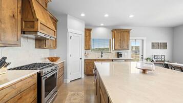 A modern kitchen with wooden cabinets, a large island, and a built-in oven.