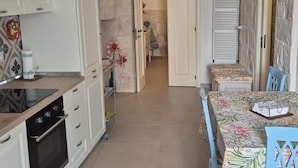 A kitchen with white cabinets, a black oven, and a dining area with a floral tablecloth.