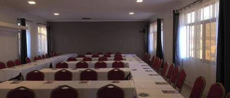 A conference room with long tables and red chairs, equipped with nameplates and brochures.