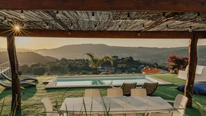 A poolside area with a pergola overhead, a pool, and a view of the surrounding landscape. - Villa Cantinho da Cavadinha (Burgo)