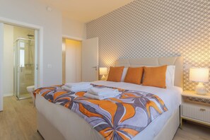 Une chambre d’hôtel comprenant un lit, une table de chevet, une lampe et un espace douche.