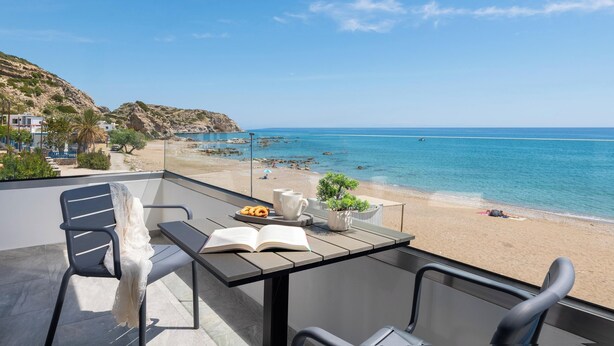 Ein Balkon mit Tisch, Stühlen und Blick auf Strand und Meer.