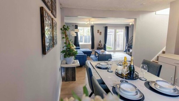 A dining area with a table set for four, a potted plant, and a view of the backyard. - Cozy House in Central Andover (Parking, 65” TV) (Andover)