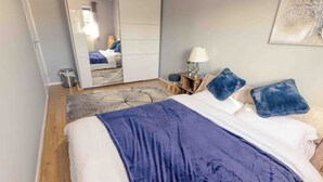 A bedroom with a bed, a mirror, a nightstand, and a lamp. - Cozy House in Central Andover (Parking, 65” TV) (Andover)