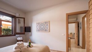 A hotel room with a bed, a wall-mounted TV, a decorative wall piece, and a door leading to another room. - Villaelena in Marittima (Marittima)