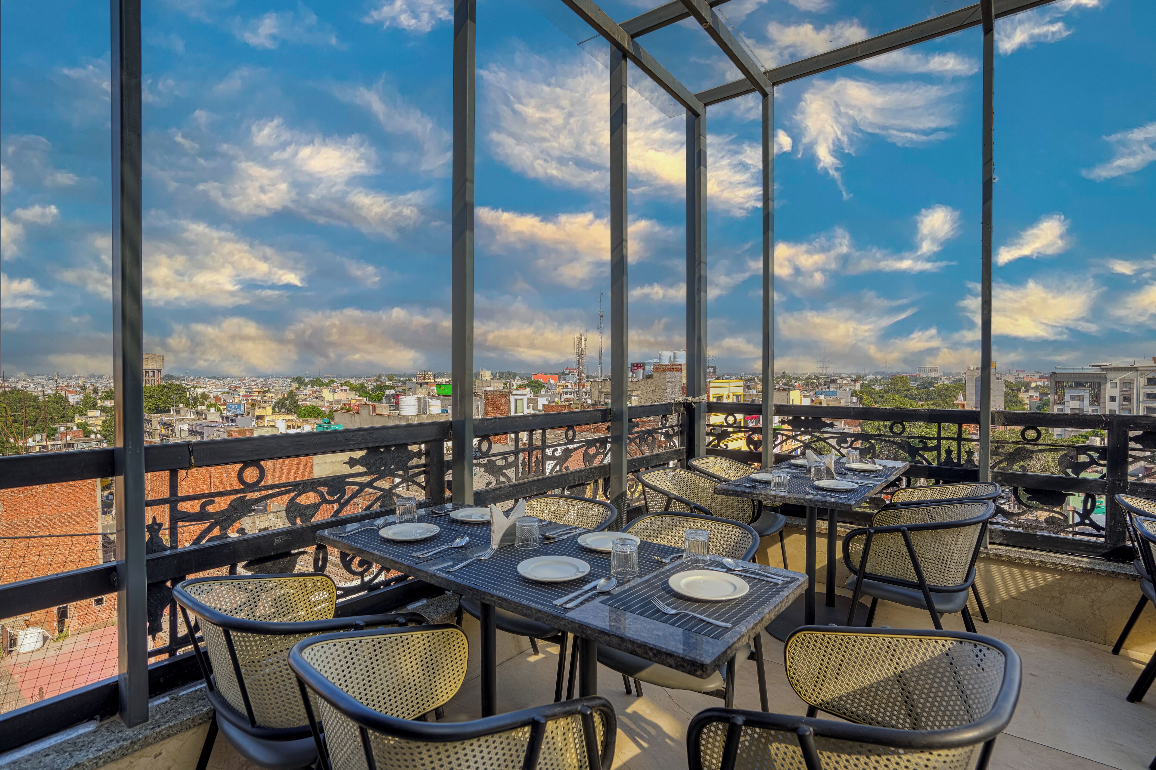 Una terraza en la azotea con mesas y sillas, que ofrece vistas de la ciudad.