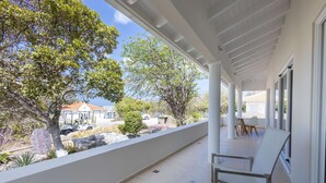 A covered balcony with a view of a residential area, including a house and parked cars. - Ser na Private Retreat (St. Marie)