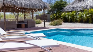 A pool area with lounge chairs and thatched-roof structures. - Ser na Private Retreat (St. Marie)