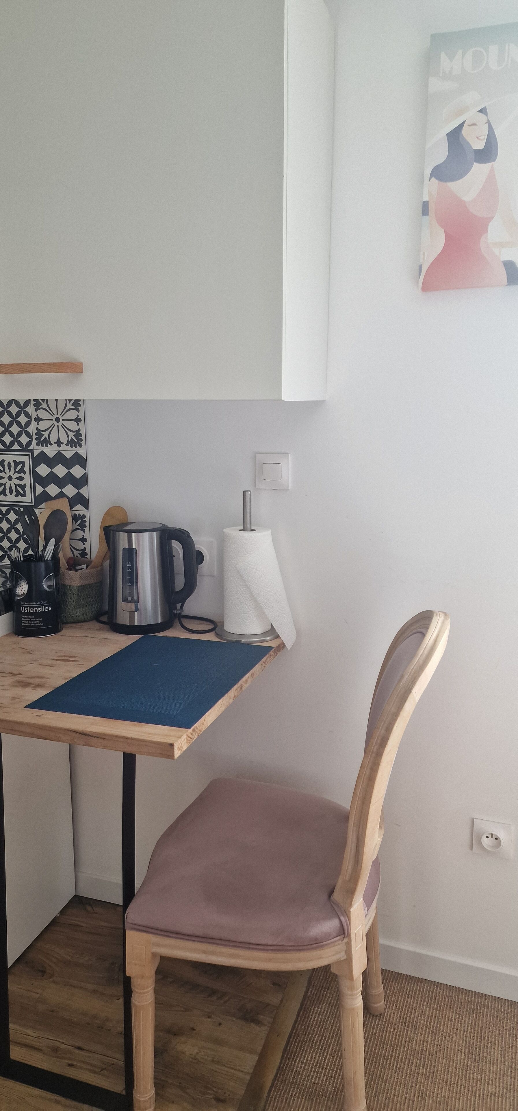A kitchen with a wooden table, a kettle, a coffee maker, and a chair.