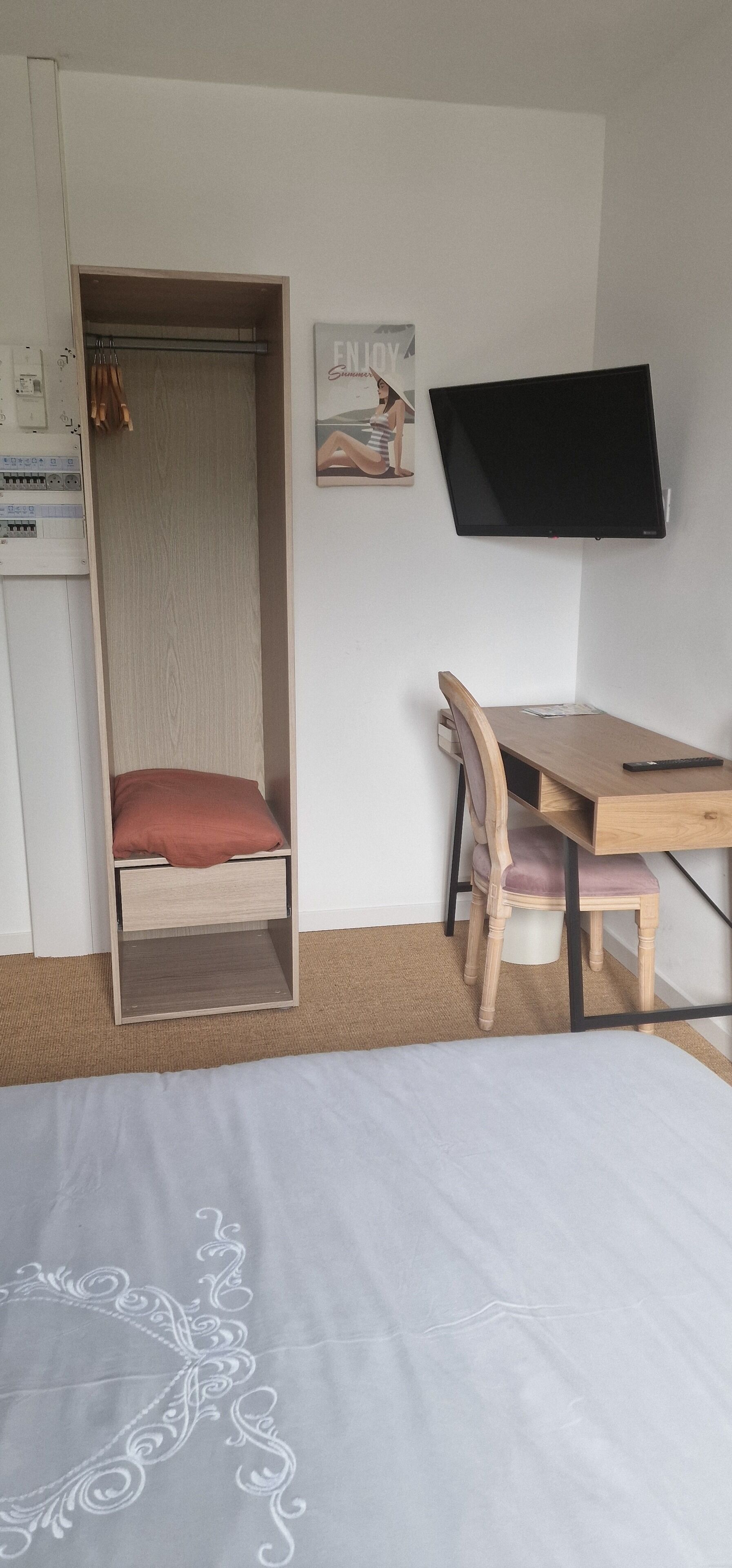 A bedroom with a bed, a desk, a chair, a TV, and a wardrobe.