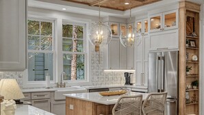 A modern kitchen with a central island, pendant lights, and built-in cabinetry. - Stunning Down-to-the-Studs Remodel  – Across from Camp WaterColor (Santa Rosa Beach)