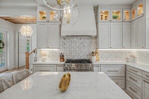 A modern kitchen with white cabinetry, a central island, and a stainless steel stove.