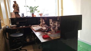 Un escritorio desordenado con varios objetos, una estatua y una planta en maceta.