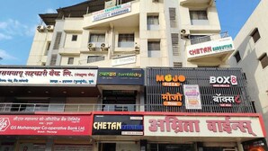 Un edificio de varios pisos con diversos comercios en la planta baja, como un banco, una pizzería y un servicio de comida para llevar.