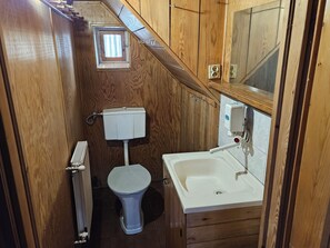 Un baño pequeño con inodoro, una ventana y un lavabo.