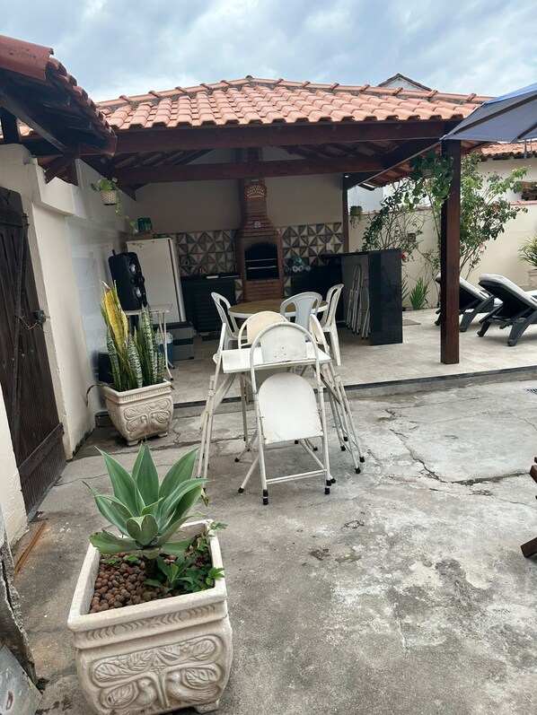 A patio with a table and chairs, a brick oven, and potted plants.