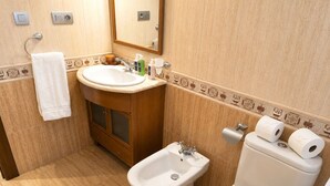 Et badeværelse med vask, bidet, toilet og håndklædestang.