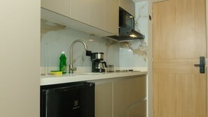 A compact kitchen with a black refrigerator, a coffee maker, and a wooden door. - NOK Spacious Duplex in Parque 93 (Bogotá)