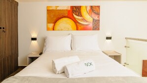A hotel room with a bed, two bedside tables, a painting on the wall, and a towel with "NOK" on it. - NOK Spacious Duplex in Parque 93 (Bogotá)