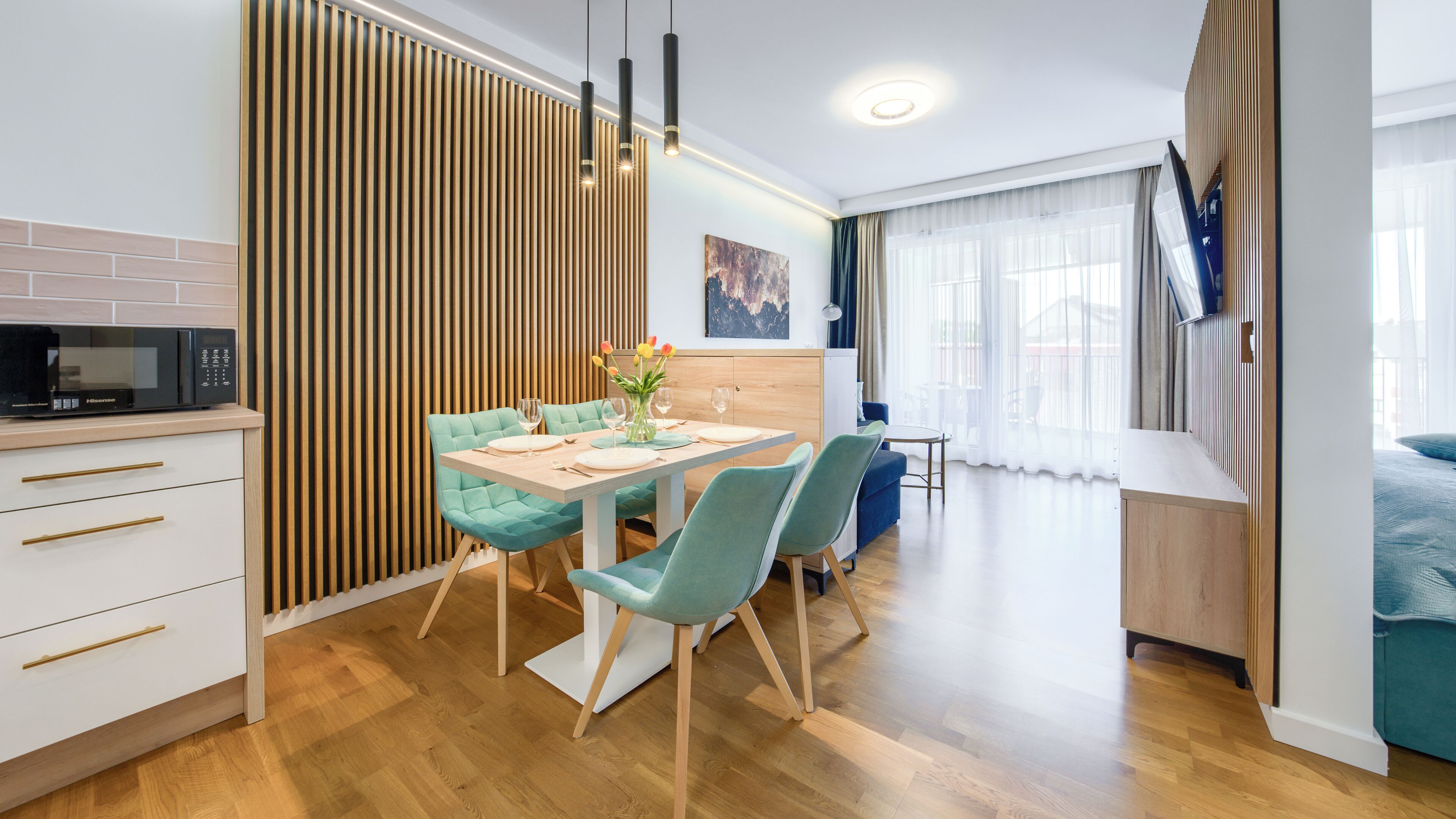 A modern kitchen with a microwave, wooden panel wall, and a dining area with a table set for two.