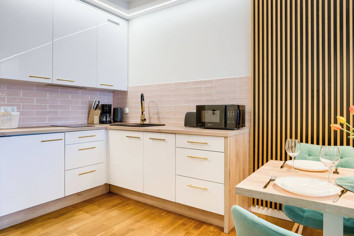 A modern kitchen with white cabinets, a wooden countertop, and a dining area with a table set for two.
