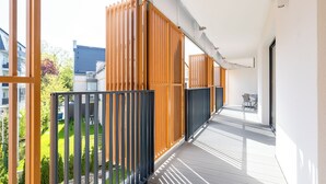 Un balcón con vistas a un jardín y edificios cercanos.