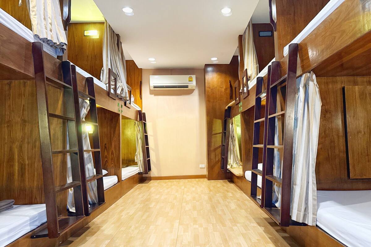 A corridor with bunk beds, wooden walls, and an air conditioning unit.