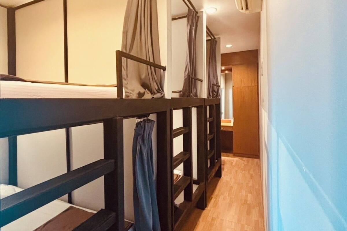 A corridor with bunk beds, a wooden floor, and a door at the end.